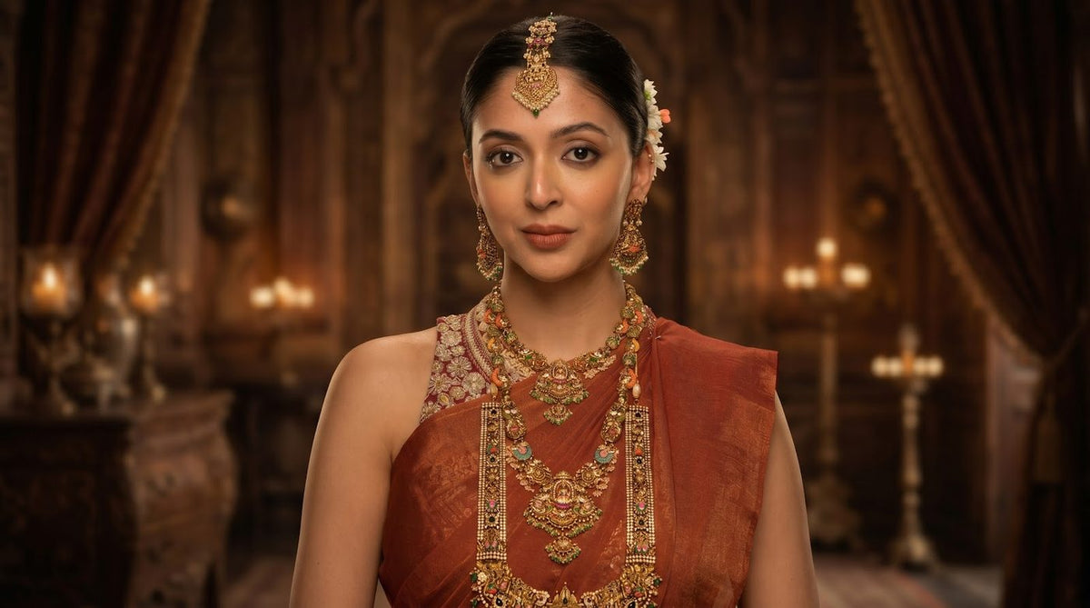 A woman in a temple necklace, jhumka earrings and a maang tikka.